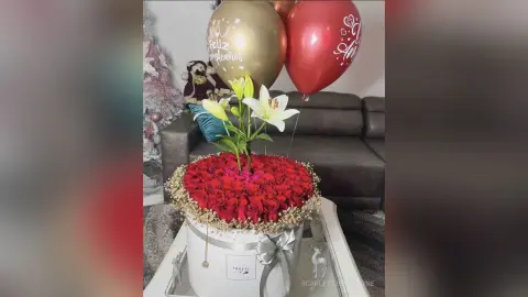 Elegant red rose bouquet in a white gift box with gold balloons for a romantic birthday celebration.