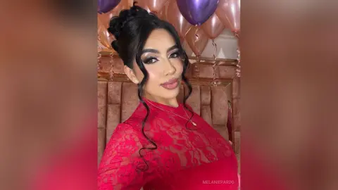 Glamorous woman in a red lace dress celebrating with pink balloons in a festive indoor setting.