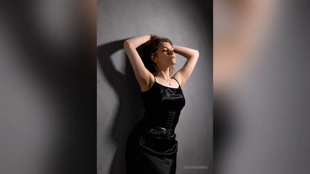 Elegant woman in a black lace corset top posing with moody lighting in a studio setting.