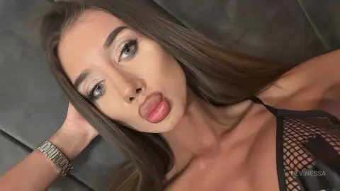 DeviNessa pouts her lips while lying back, wearing a black mesh top and a silver watch.