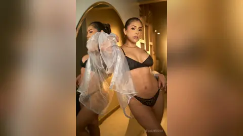 EvaCarusso poses in a black lace bra and panties, wearing a sheer white robe while looking into a mirror.
