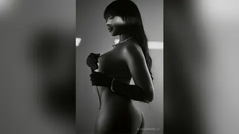 Elegant woman in black gloves and pearl necklace posing in a moody black and white silhouette portrait.