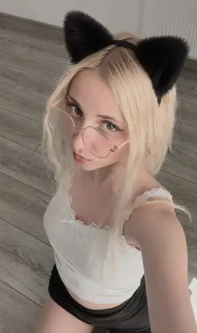 Blonde woman in white lace camisole and cat ears posing indoors with a soft, playful mood.