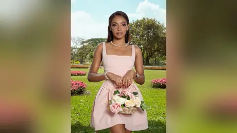 Elegant woman in a pink cocktail dress holding a flower basket in a sunny garden setting.