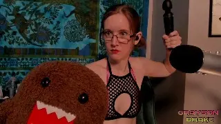 Redheaded woman in a black mesh top sitting in a cozy room with a large shark plushie.