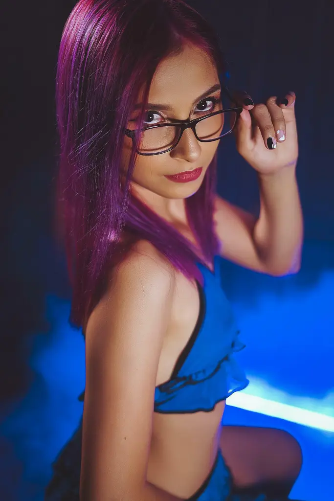 alicejacob poses with red lighting, showing her face, hair, and bare shoulders in a dark setting.