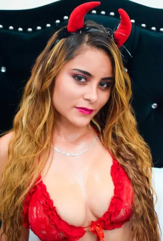 CharlotteCollins poses in a red lace bra and red devil horns, showing off her long blonde hair and cleavage against a dark background.