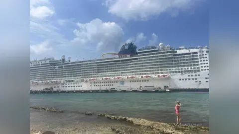 Large Norwegian Epic cruise ship docked in turquoise tropical waters under a bright blue sky.