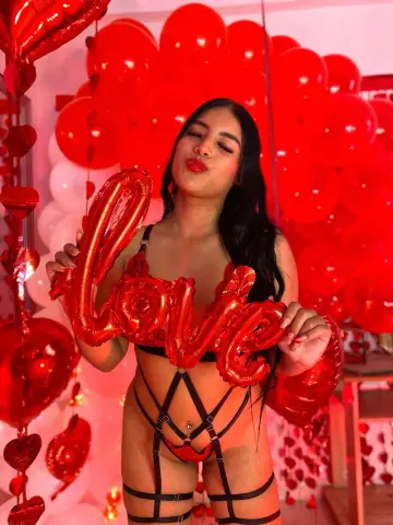 Young woman in black lace lingerie posing with red heart balloons for a romantic Valentine's Day mood.