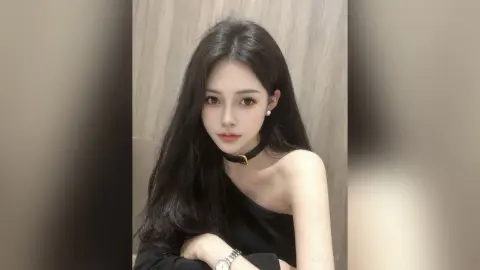 AgelaHui poses with long black hair wearing a black one-shoulder top and a black choker against a neutral wall.