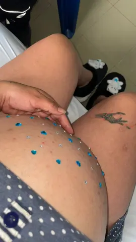 Close-up of a woman in polka dot shorts with blue glitter accents on her skin and a hand tattoo.