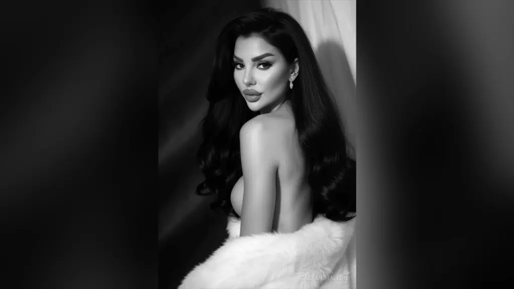 Glamorous woman in a black and white faux fur coat posing with elegant makeup in a moody studio setting.