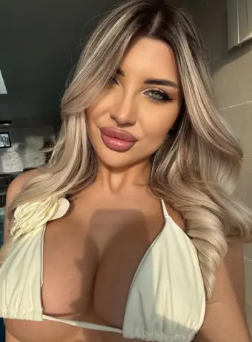 Blonde woman in a cream floral bikini top posing in bright sunlight for a summer lifestyle look.