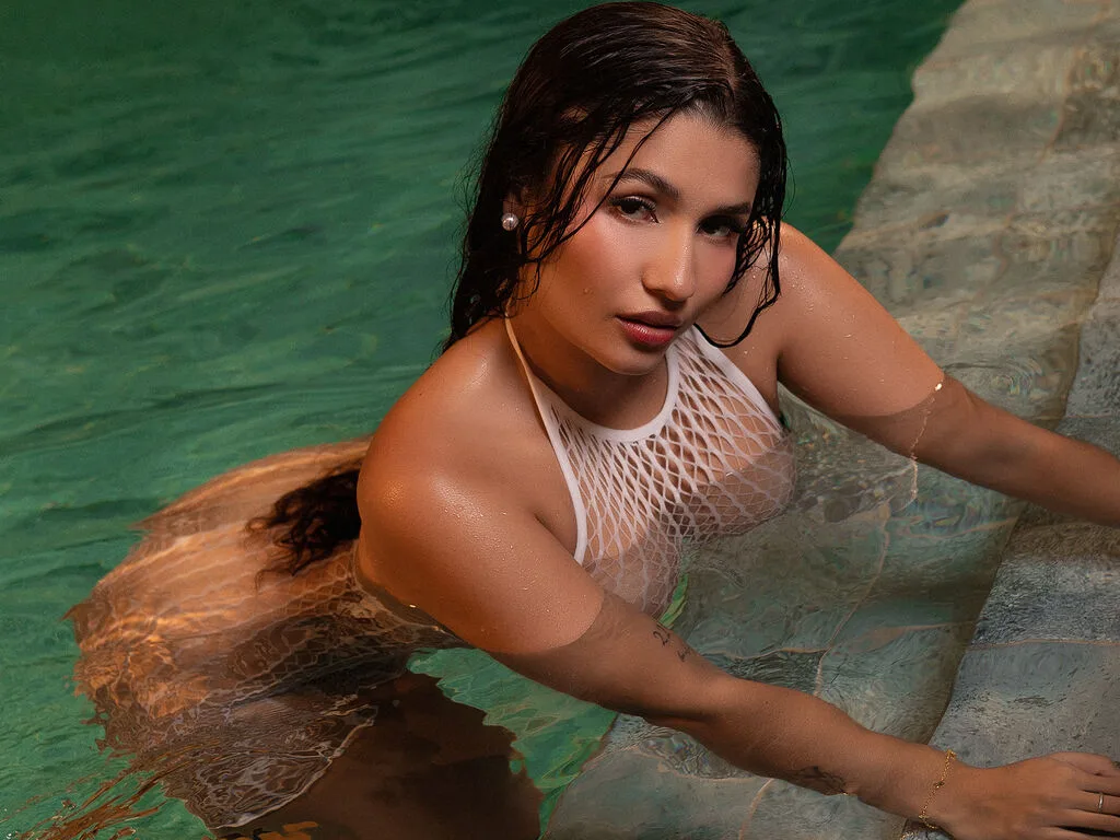 TracyMoore sits in a white bathtub wearing a green satin dress and holding a glass of champagne.