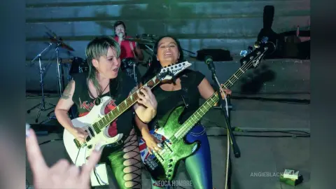 Energetic female rock singers performing live on stage in black outfits at a concert venue.