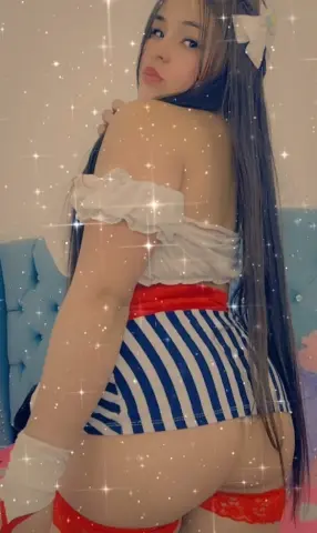 Young woman in a white off-the-shoulder top and blue striped skirt posing in a dreamy, sparkling setting.