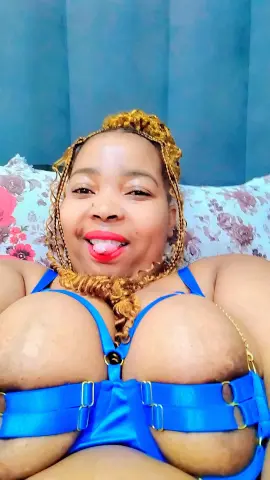 SexyChubbyxx29 smiles while wearing a bright blue bra and laying on a floral pillow.