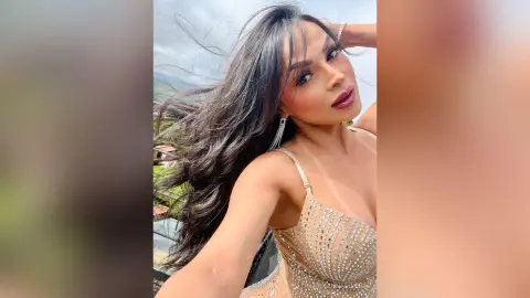 Glamorous woman in a sparkling sequin cocktail dress posing outdoors with wind-swept hair.