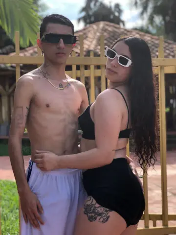 Young couple in swimwear posing outdoors near a wooden fence on a sunny summer day.