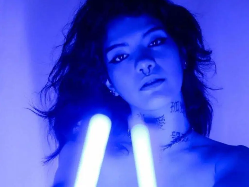 Moody portrait of a young woman with dark hair under blue neon lighting for a cinematic aesthetic.