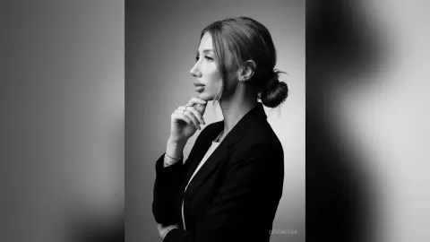 DeviNessa poses in profile, resting her chin on her hand while wearing a black blazer.