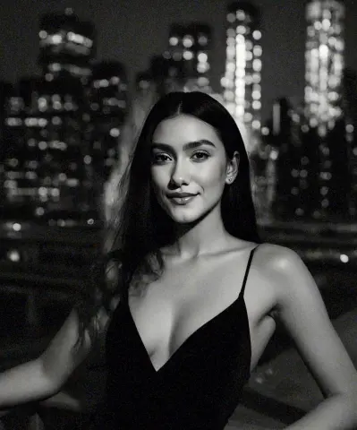 Smiling young woman in a black slip dress against a blurred night city skyline background.