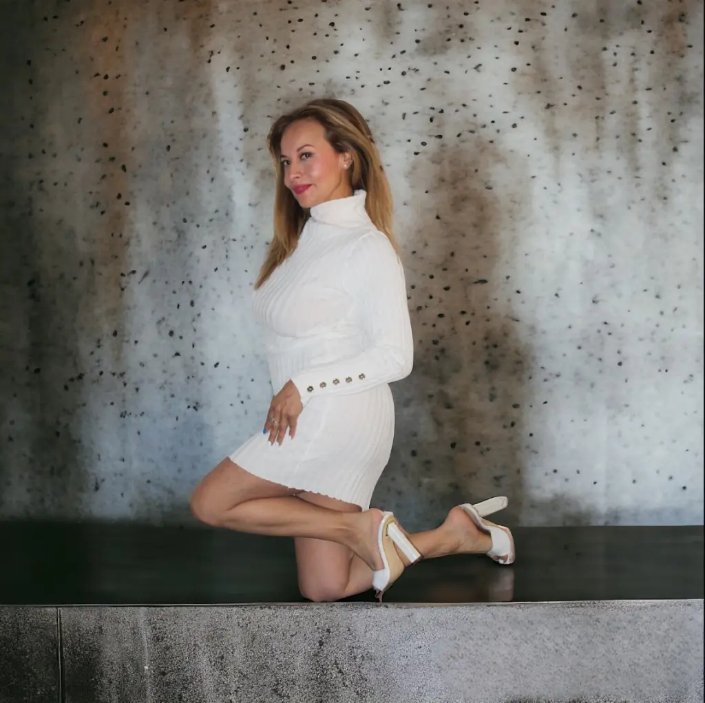 MeiMartin poses in a white babydoll nightie, showing off her long blonde hair and bare legs against a plain white background.