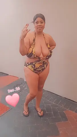 Curvy woman in a patterned gold and black bikini posing outdoors on a sunny day.