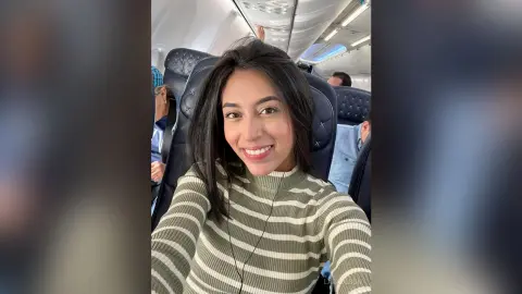 Smiling young woman in a striped sweater enjoying a flight on an airplane.