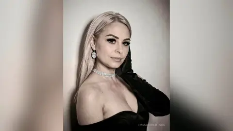 Elegant blonde woman in a black evening dress and diamond choker posing for a glamorous portrait.