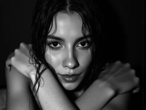 Close-up black and white portrait of a young woman with wet hair posing with a moody, soulful expression.