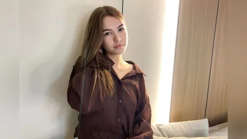 PaisleyMoore — PaisleyMoore leans against a wall wearing a brown button-down shirt.
