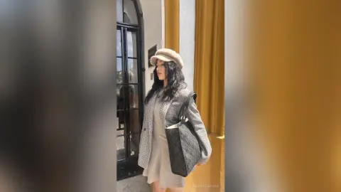 Stylish woman in a grey plaid blazer and beige beret standing by a classic doorway in a chic urban setting.