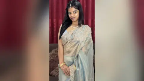 Sejuti poses in a light blue, silver-trimmed saree with her long black hair down and a pearl necklace.