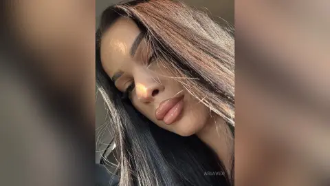 AriaVex poses with long, dark hair partially covering her face and full, glossy lips.