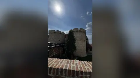 Ancient stone castle towers under a bright sunny sky with a serene historical atmosphere.