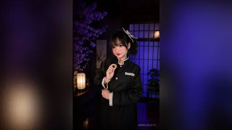 Young woman in elegant black traditional attire posing in a moody, dimly lit room with purple floral accents.