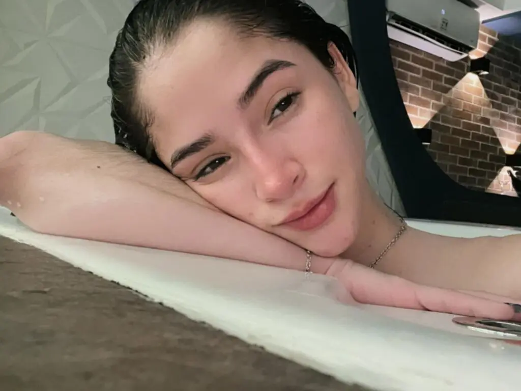 CamilaMalkovich rests her chin on her arms while looking directly at the camera with wet, dark hair.