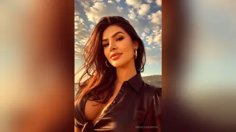 Beautiful brunette woman in a black silk blouse smiling under a golden sunset sky.