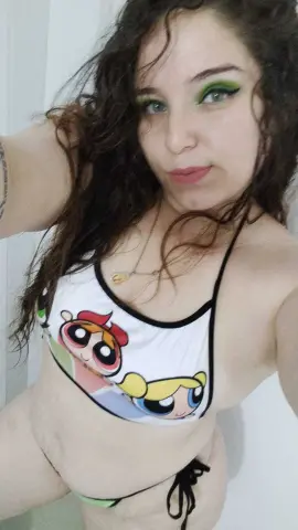 Young woman with long wavy hair wearing a white graphic bikini top in a bright indoor setting.