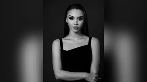 KendallMinx poses in a black tank top against a dark background in this black and white portrait.