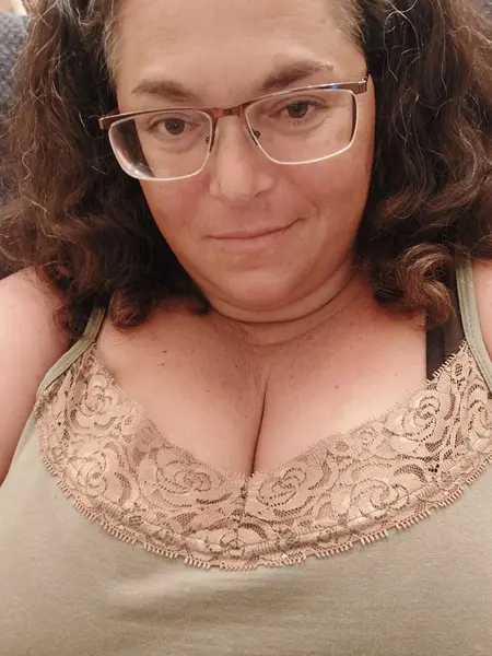 Supervagtastic looks at the camera wearing glasses and a red top, showing her dark hair and a beaded necklace.