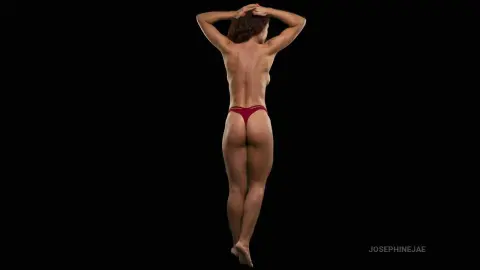 Athletic woman in red bikini bottoms posing against a black background with a minimalist mood.