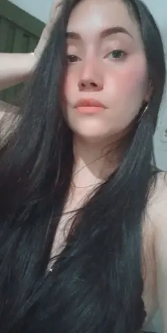 Young woman with long dark hair posing in a casual indoor setting with a soft, natural mood.