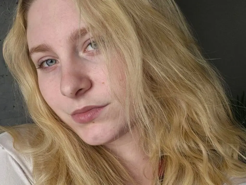 StellaVanilla looks at the camera with her long blonde hair framing her face in a close-up headshot.