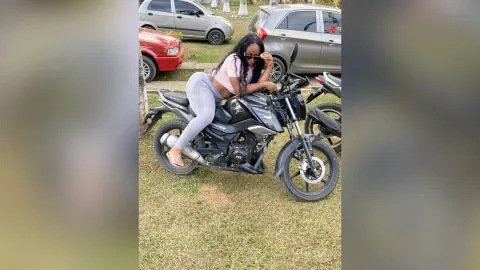 KattyLeya — KattyLeya sits on a black motorcycle wearing a pink crop top and tight grey leggings.