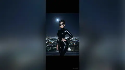 Woman in a sleek black catsuit posing against a glowing city skyline under a night moon.
