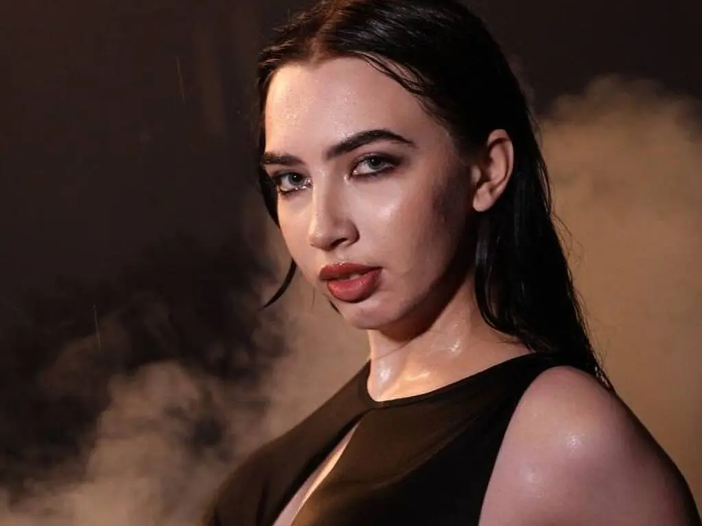Moody portrait of a woman in a black sleeveless top against a dark, smoky background.