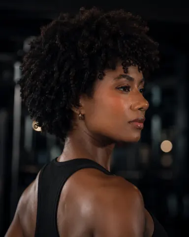 KylieDecks — KylieDecks poses in a black tank top with her dark curly hair styled in an afro.
