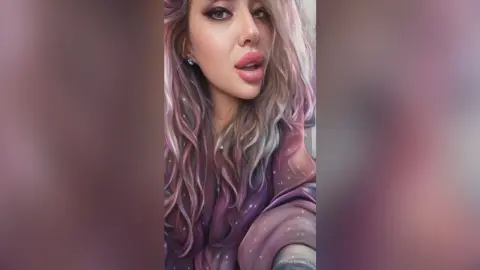 Portrait of a blonde woman with glamorous makeup wearing a purple sequined top in a soft, dreamy setting.